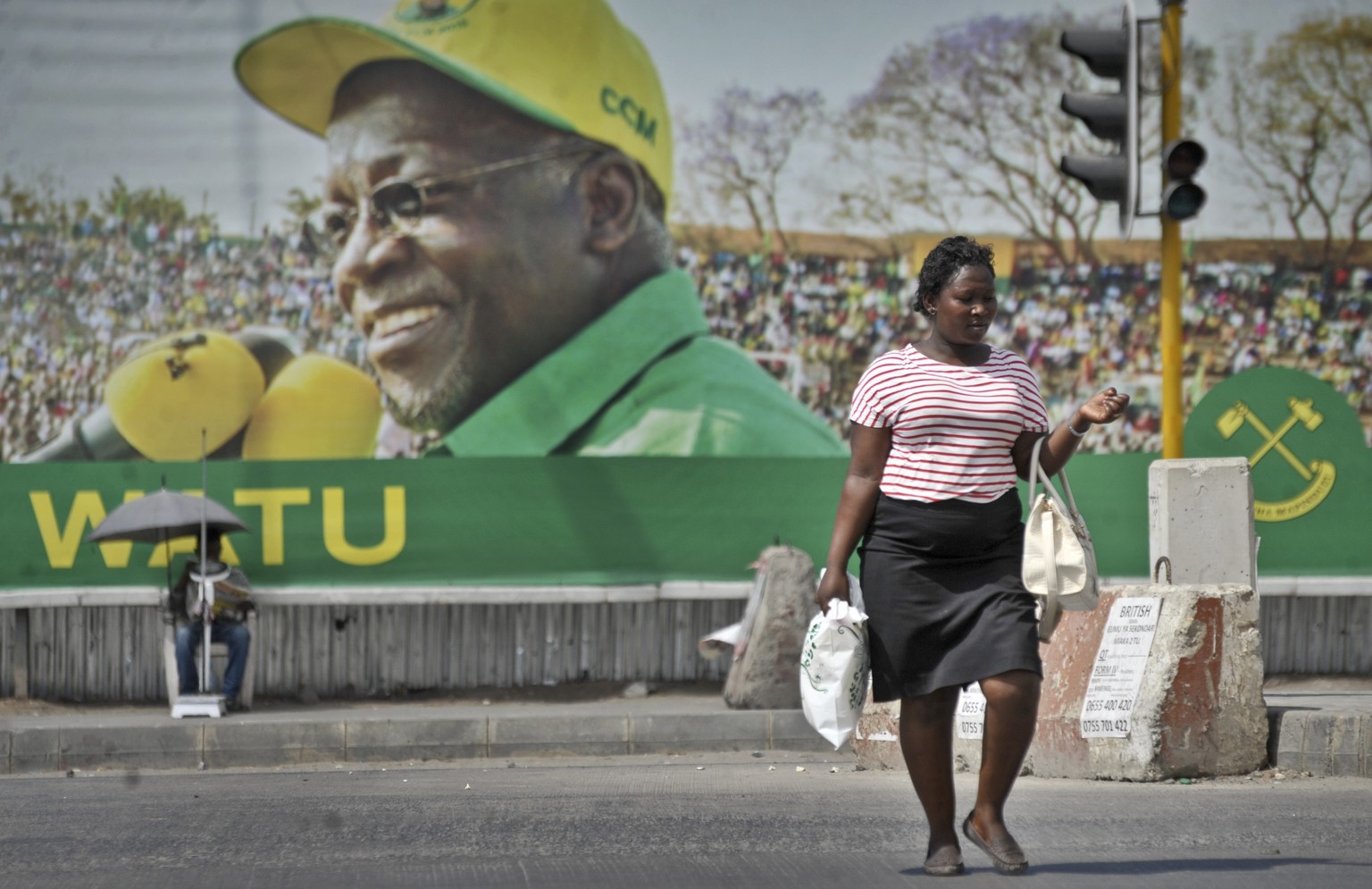 FILE - In this Oct. 26, 2015 file photo, a Tanzanian woman walks past a billboard for the ruling party&#039;s then presidential candidate John Magufuli, in Dar es Salaam, Tanzania. President John Magu ...