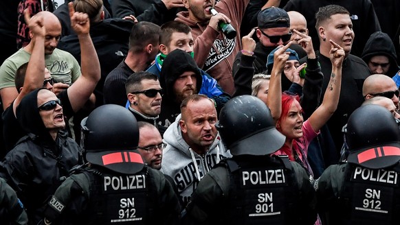 epa06977355 Right wing protesters gesture towards police in riot gear as they gather at the place where a man was stabbed in the night of the 25 August 2018, in Chemnitz, Germany, 27 August 2018. A 35 ...