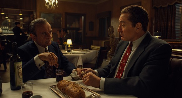 Dipping bread in wine, known as Intinction, speaks to the shared Catholic traditions of Russell Bufalino (Joe Pesci) and Frank Sheeran (Robert De Niro). © 2019 Netlfix US, LLC. All rights reserved.