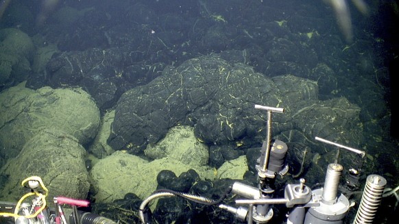 This 2015 image provided by the Woods Hole Oceanographic Institution shows the edge of the 2015 lava flow, above, at the Axial Seamount where it overlies older sedimented lavas, bottom. A study in the ...