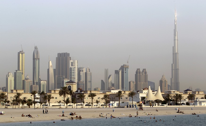 In this photo dated Thursday, July 26, 2012, people enjoy swimming at Jumeirah open beach with the city skyline in background, Dubai, United Arab Emirates. Not all Dubai beaches are hidden behind high ...