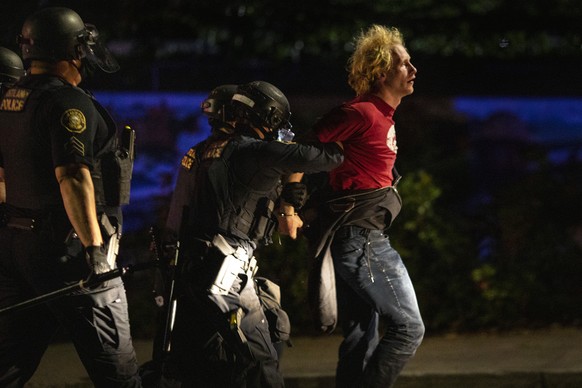 Portland police make arrests on the scene of the nightly protests at a Portland police precinct on Sunday, Aug. 30, 2020 in Portland, Ore. Oregon State Police will return to Portland to help local aut ...