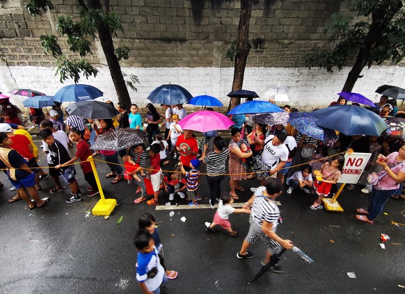 epa08089500 Residents holding umbrellas queue during a gift giving event on Christmas day in Las Pinas city, Philippines, 25 December 2019. Typhoon Phanfone, (locally known as Ursula), made landfall i ...
