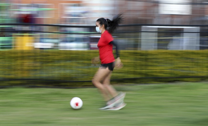 Wearing a face mask, Venezuelan soccer player María Alejandra Peraza, who played last season with Colombia&#039;s Millonarios women&#039;s team, trains alone at a park in Bogota, Colombia, Thursday, M ...