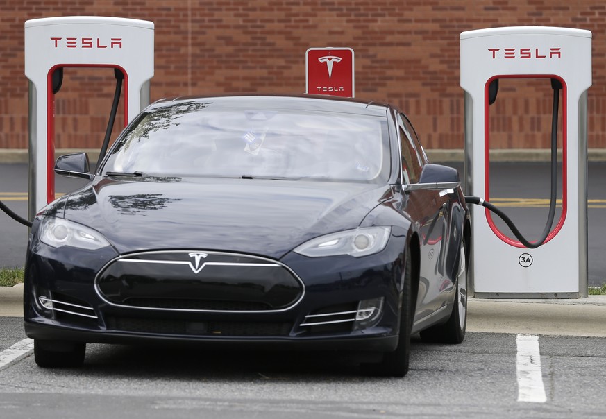 FILE- In this June 24, 2017, file photo, a Telsa car recharges at a Tesla charging station at Cochran Commons shopping center in Charlotte, N.C. Tesla Inc. reports earnings Wednesday, Feb. 7, 2018. (A ...
