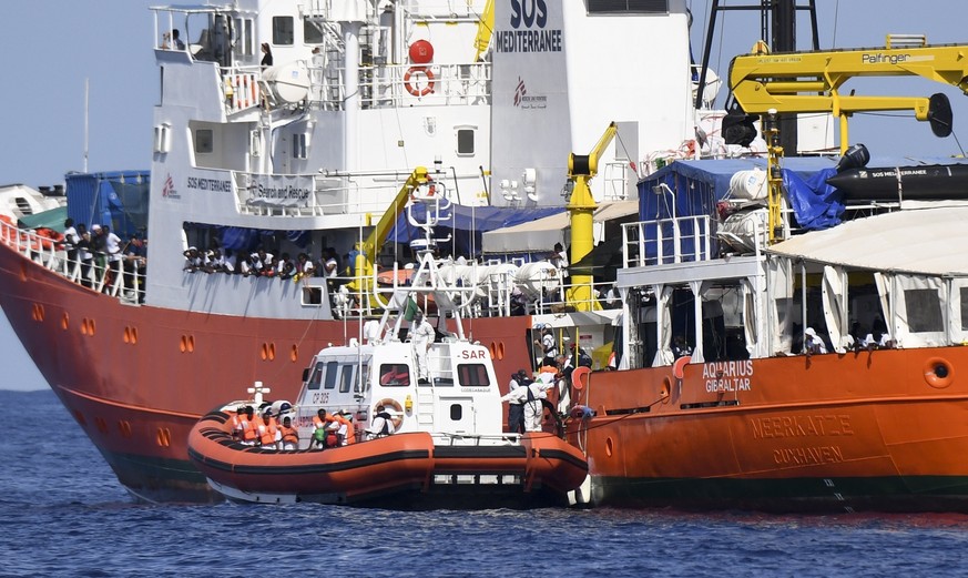 An Italian Coast Guard boat approaches the French NGO &quot;SOS Mediterranee&quot; Aquarius ship as migrants are being transferred, in the Mediterranean Sea, Tuesday, June 12, 2018. Italy dispatched t ...
