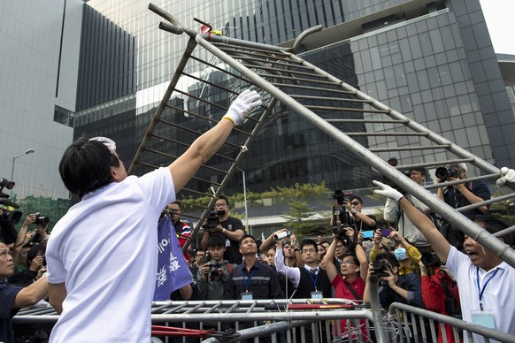 Demonstranten, Polizisten und Bauarbeiter entfernen die Barrikaden ausserhalb des Citic Tower im Stadtteil Admiralty.
