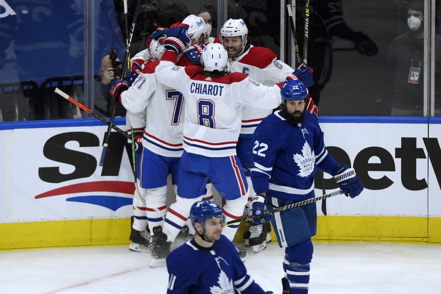 Toronto Maple Leafs defenseman Zach Bogosian (22) skates past as Montreal Canadiens players mob teammate Brendan Gallagher (11) following his goal during second period NHL Stanley Cup hockey action in ...