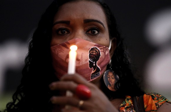 A woman carries a candle during a vigil to protest against the murder by security guards of Joao Albert Silveira Freitas after breaking into the store at the Carrefour supermarket, in Brasilia, Brazil ...