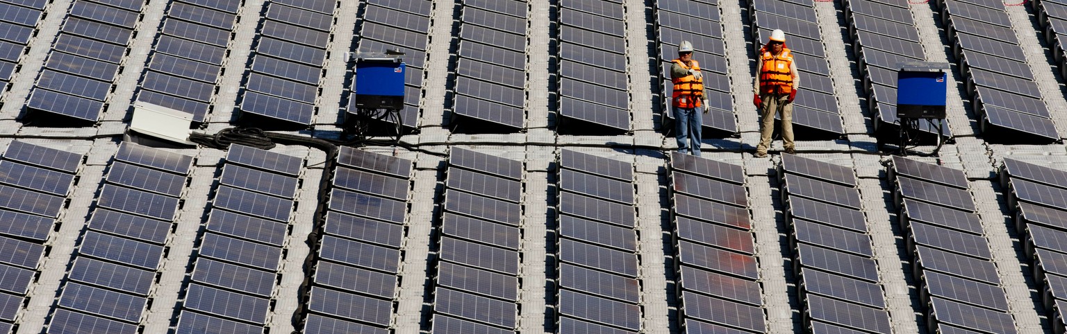 Workers stand on a floating island of solar panels on a pond at Los Bronces mine, about 65 kilometers (approximately 40 miles) from Santiago, Chile, Thursday, March 14, 2019. The 1,200-square-foot arr ...