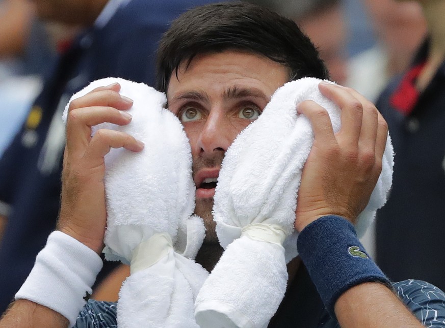 Novak Djokovic, of Serbia, puts an ice towel to his face during a changeover in his match against Marton Fucsovics, of Hungary, during the first round of the U.S. Open tennis tournament, Tuesday, Aug. ...