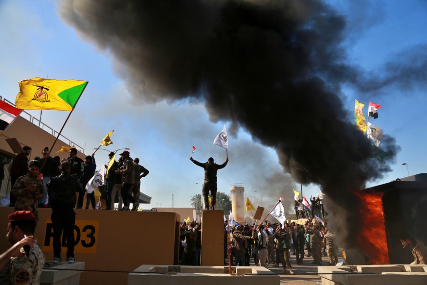 Protesters burn property in front of the U.S. embassy compound, in Baghdad, Iraq, Tuesday, Dec. 31, 2019. Dozens of angry Iraqi Shiite militia supporters broke into the U.S. Embassy compound in Baghda ...