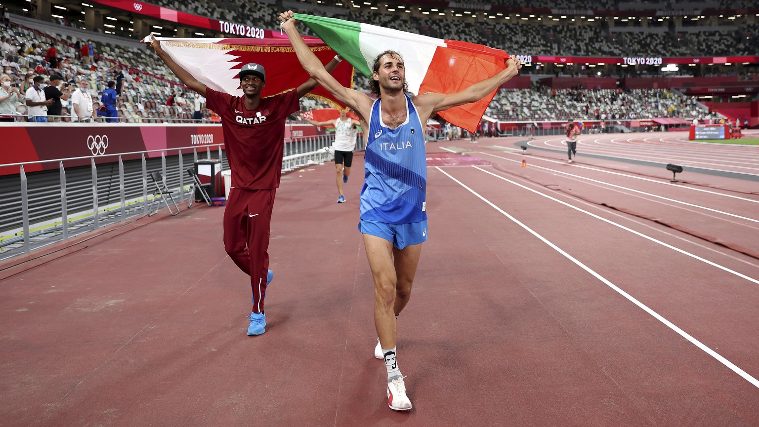 Gold medalist Mutaz Barshim, left, of Qatar and silver medalist Gianmarco Tamberi of Italy celebrate on the track after the final of the men&#039;s high jump at the 2020 Summer Olympics, Sunday, Aug.  ...