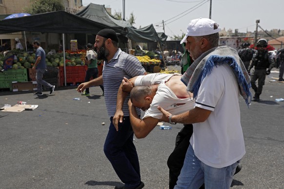 epa06101062 Palestinians carry a wounded Palestinian from the scene after Israeli Border Police threw stun grenades at the end of a mass Friday prayer in the East Jerusalem neighborhood of Ras al-Amud ...