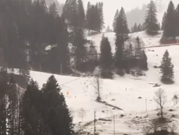 Ein Heli (links) fliegt in Engelberg Schnee für die Talabfahrt ein.