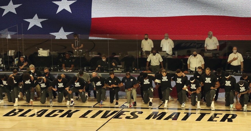 Players and coaches kneel during the national anthem before the Utah Jazz against the New Orleans Pelicans NBA basketball game Thursday, July 30, 2020, in Lake Buena Vista, Fla. (Charles King/Orlando  ...