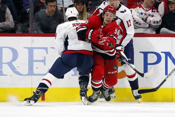 Carolina Hurricanes&#039; Erik Haula (56) tries to control the puck as he is hit by Washington Capitals&#039; Nick Jensen (3) during the third period of an NHL hockey game in Raleigh, N.C., Saturday,  ...