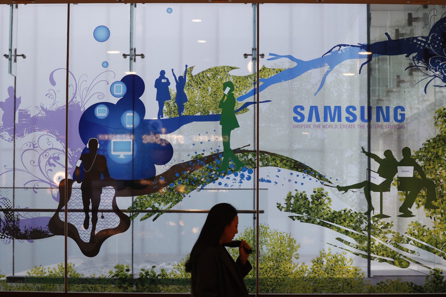 epa07268796 A South Korean woman stands next to a Samsung advertisement at the Samsung Electronics headquarters in Seoul, South Korea, 08 January 2019. Samsung Electronics Co. said on 08 January its o ...