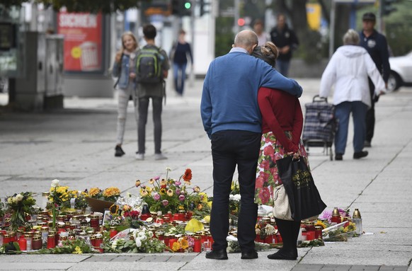 Two people stay next to candles and flowers in Chemnitz, Germany, Thursday, Aug. 30, 2018. The governor the German state of Saxony, Michael Kretschmer, traveled Thursday to the city where anger over t ...