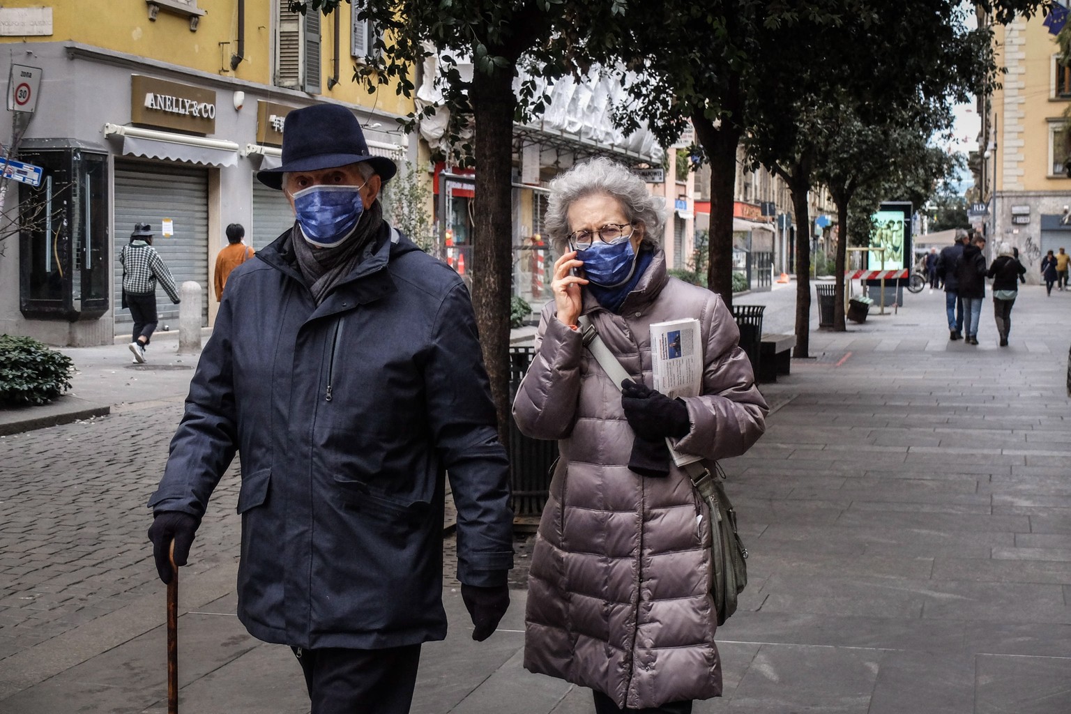 epa08249348 Two passers-by wear a protective face mask as they walk in Milan, Italy, 26 February 2020. Civil Protection Chief Angelo Borrelli said that the number of people which have died due to the  ...