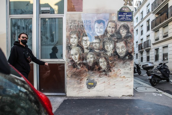 epa08640768 A pedestrian passes a painting depicting Charlie Hebdo&#039;s killed cartoonists, by French street artist Christian Guemy, outside the satirical newspaper Charlie Hebdo&#039;s former offic ...