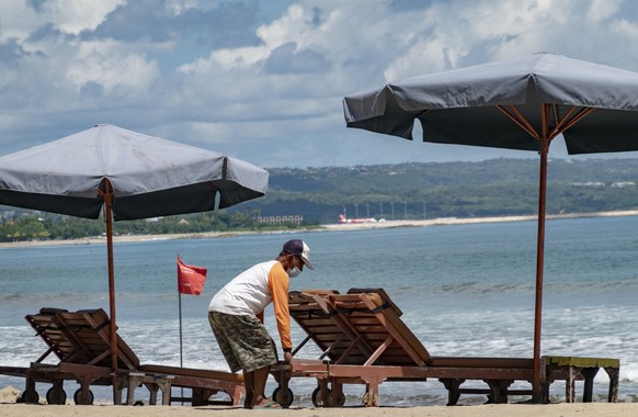 epa09146519 A man sets up sea-side loungers at a beach in Kuta, Bali, Indonesia, 20 April 2021. Indonesian government planned to open the resort islands of Bali for foreign tourists by the end of July ...