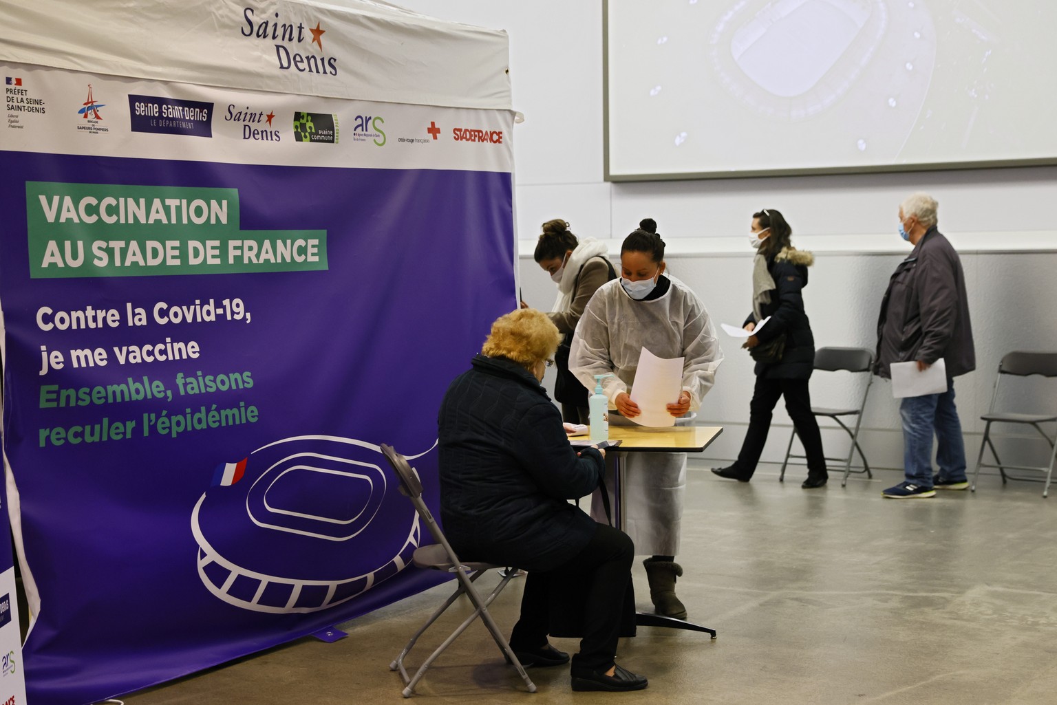epa09118079 People fill forms upon their arrival to be vaccinated against Covid-19 at a vaccination centre set up at the Stade de France (France&#039;s Stadium), in Saint-Denis, outside Paris, France, ...