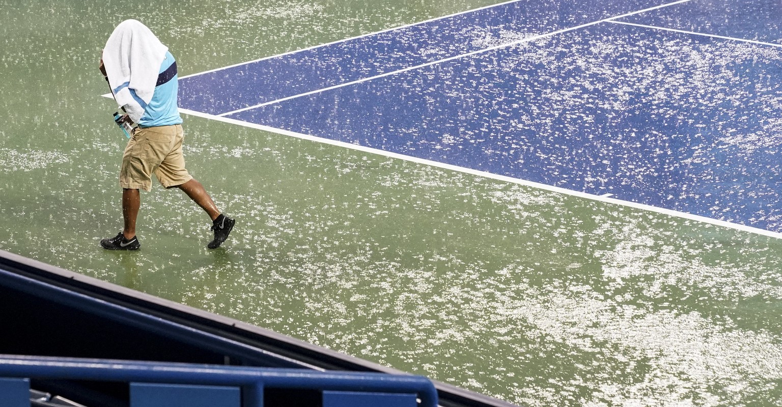A court attendant moves toward shelter after play was suspended due to rain at the Western &amp; Southern Open tennis tournament Thursday, Aug. 16, 2018, in Mason, Ohio. (AP Photo/John Minchillo)