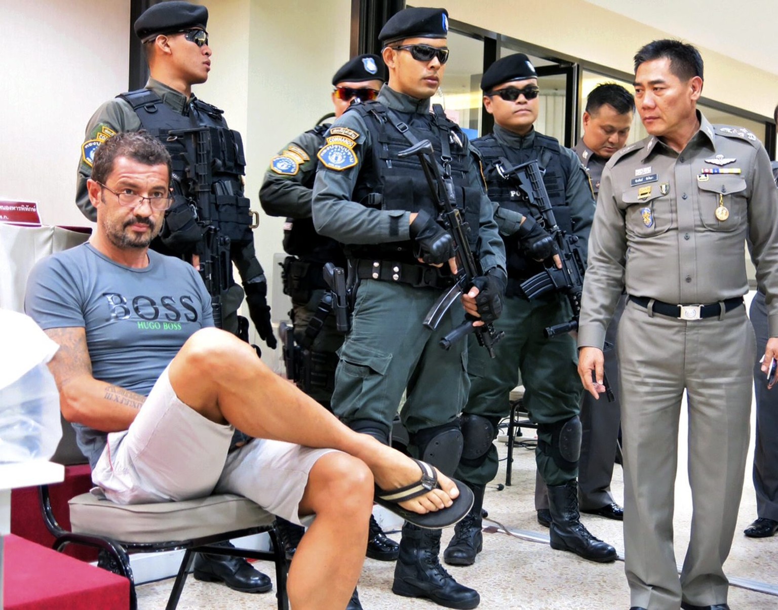 epa04866212 A photo made available on 30 July 2015 shows Andre Xavier Justo (L), Swiss national, alleged blackmail his former employer sits next to armed Thai police officers during a press conference ...