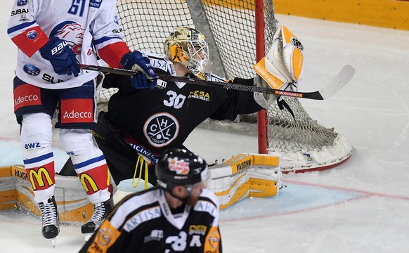 Zurich&#039;s player Fabrice Herzog, left, fights for the puck with Lugano’s goalkeeper Elvis Merzlikins, right, during the sixth leg of the Playoffs quarterfinals game of National League A (NLA) Swis ...