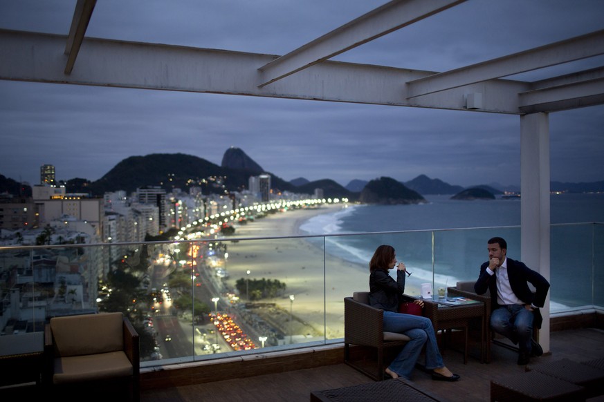 FILE - In this Aug. 16, 2013, file photo, tourists sit in a bar at a hotel overlooking Copacabana beach, in Rio de Janeiro, Brazil. Despite the seeming abundance of riches for travelers, Brazil has a  ...
