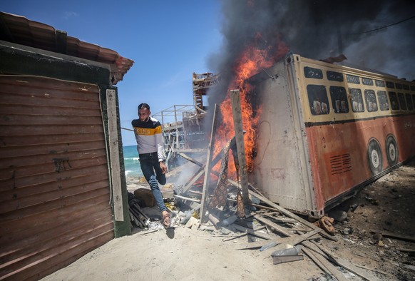epa09206860 A Palestinian runs for cover from the fire at the site of Israeli strikes in Gaza City, 17 May 2021. Three Palestinians were reportedly killed after Israeli air strikes. In response to day ...