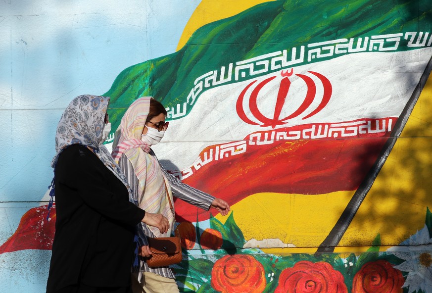 epa08570960 Iranian women wearing face masks walk past a mural of Iran&#039;s national flag in Tehran, Iran, 28 July 2020. According to figures released by the Iranian Health Ministry, Iran hits a new ...