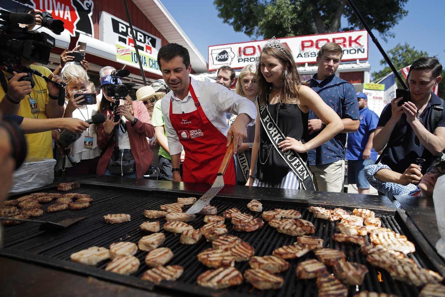 Democratic presidential candidate South Bend Mayor Pete Buttigieg helps cook pork at the Iowa State Fair, Tuesday, Aug. 13, 2019, in Des Moines, Iowa. (AP Photo/John Locher)