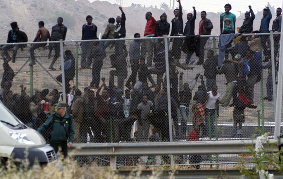 epa04187764 Dozens of immigrants climb on to the fence at the border between Morocco and Melilla in another mass attempt of crossing into the Spanish enclave in northern Africa, 01 May 2014. Some 300  ...