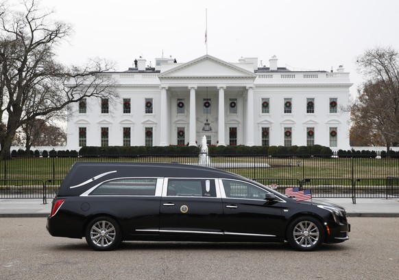 epa07210174 The hearse carrying the flag-draped casket of former President George H.W. Bush passes by the White House from the Capitol, heading to a State Funeral at the National Cathedral, in Washing ...
