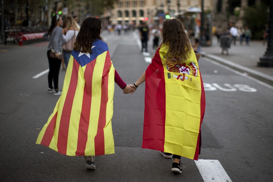 FILE - In this Tuesday Oct. 3, 2017 file photo Irene Guszman, 15, wearing a Spanish flag on her shoulders and Mariona Esteve, 14, with an &#039;estelada&#039; or independence flag, walk along the stre ...