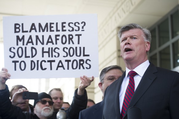 A protester holds a sign as Kevin Downing, Paul Manafort&#039;s defense attorney, speaks to reporters after Manafort was sentenced at the U.S. District Court in Washington, Wednesday, March 13, 2019.  ...