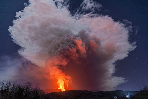 A fiery river of glowing lava flows on the north-east side of the Mt Etna volcano engulfed with ashes and smoke near Milo, Sicily, Wednesday night, Feb. 24, 2021. Europe&#039;s most active volcano has ...
