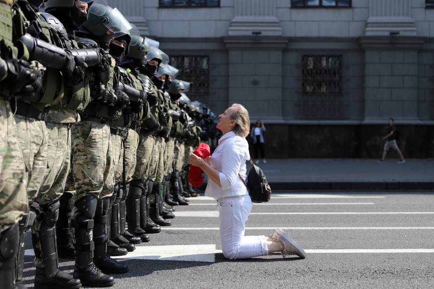 A woman kneels in front of a riot police line as they block Belarusian opposition supporters rally in the center of Minsk, Belarus, Sunday, Aug. 30, 2020. Opposition supporters whose protests have con ...