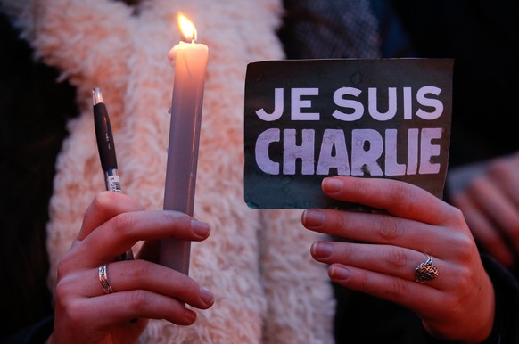 epa08094638 (FILE) - A woman holds a pencil, a candle and a sign in French reading &#039;I am Charlie&#039; as people pay their respect for the victims of a shooting at the Paris-based French satirica ...