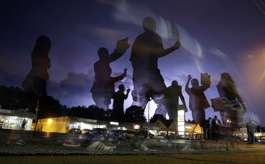 FILE - In this Aug. 20, 2014, file photo, protesters march in the street as lightning flashes in the distance in Ferguson, Mo., following the shooting of Michael Brown, an unarmed black 18-year old, i ...