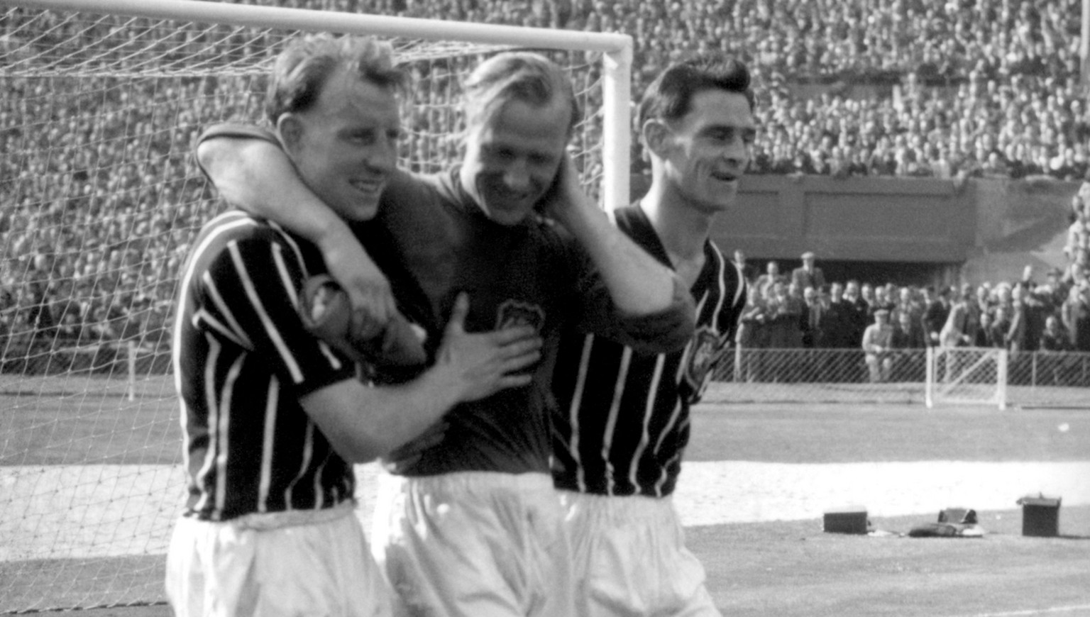 FILE - A May 5, 1956 photo from files of Bernd Trautmann, more commonly known as Bert, Manchester City&#039;s German-born goalkeeper, centre, being assisted from the pitch by two unidentified players, ...
