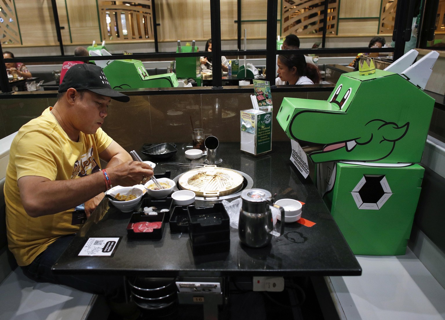 epa08442585 Diners sit next to cardboard dragons, shaped after the restaurant���s mascot, at Bar-B-Q Plaza restaurant in Bangkok, Thailand, 25 May 2020. The cutouts were placed in specific seats in or ...