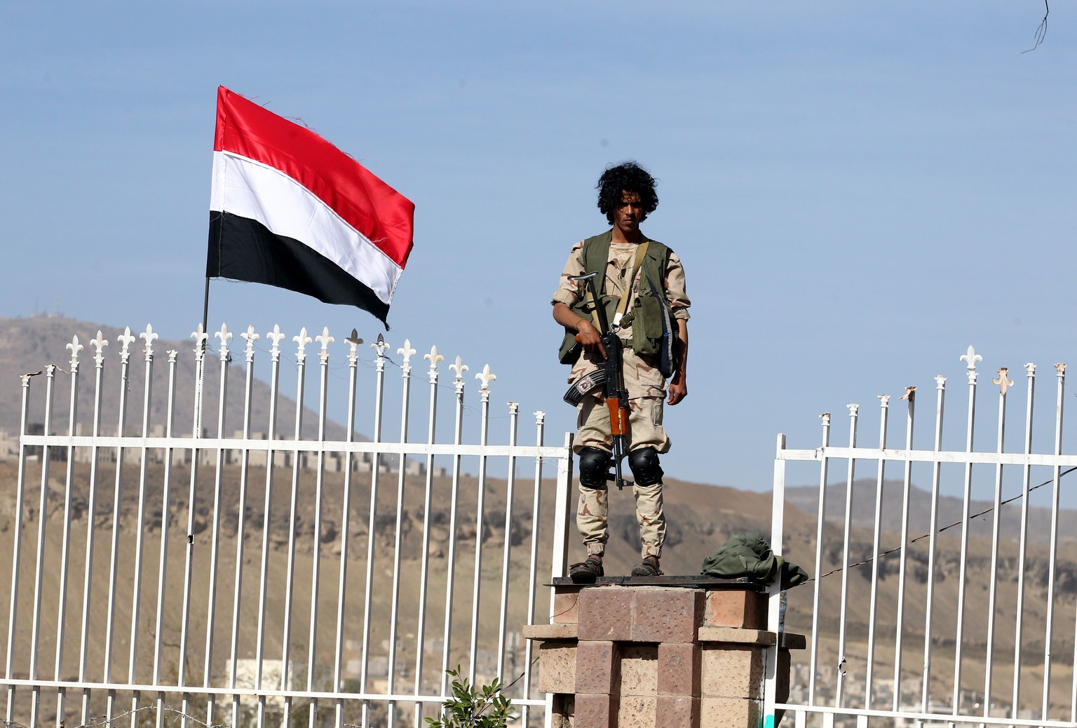 epa07464816 A Houthi militiaman stands guard near a Yemeni flag during a rally commemorating the fourth anniversary of the Saudi-led military campaign on Yemen, in Sana&#039;a, Yemen, 26 March 2019. A ...