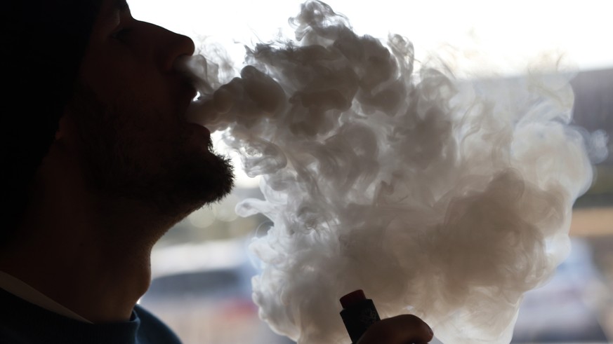 FILE - In this Friday, Jan. 18, 2019 file photo, a customer blows a cloud of smoke from a vape pipe at a local shop in Richmond, Va. Although e-cigarettes aren’t considered as risky as regular cigaret ...