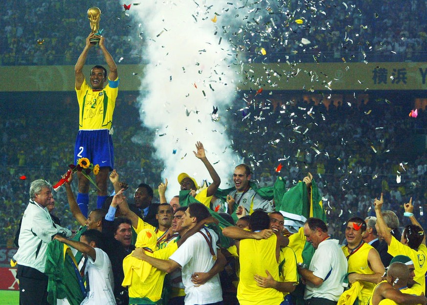 EH105 - 20020630 - YOKOHAMA, JAPAN : Brazil&#039;s team captain and defender Cafu hoists the World Cup trophy over the whole Brazilian team as confetti fall over the pitch during the award ceremony at ...