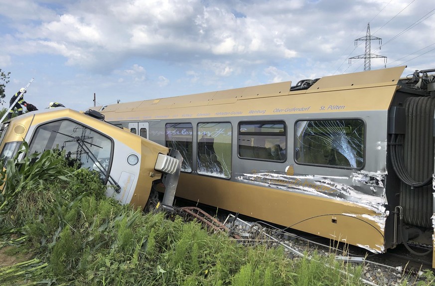 A carriage lies on its side after a train derailed near St. Poelten, Austria, Tuesday, June 26, 2018. Two people were seriously injured when the passenger train derailed on the local railway. (einsatz ...