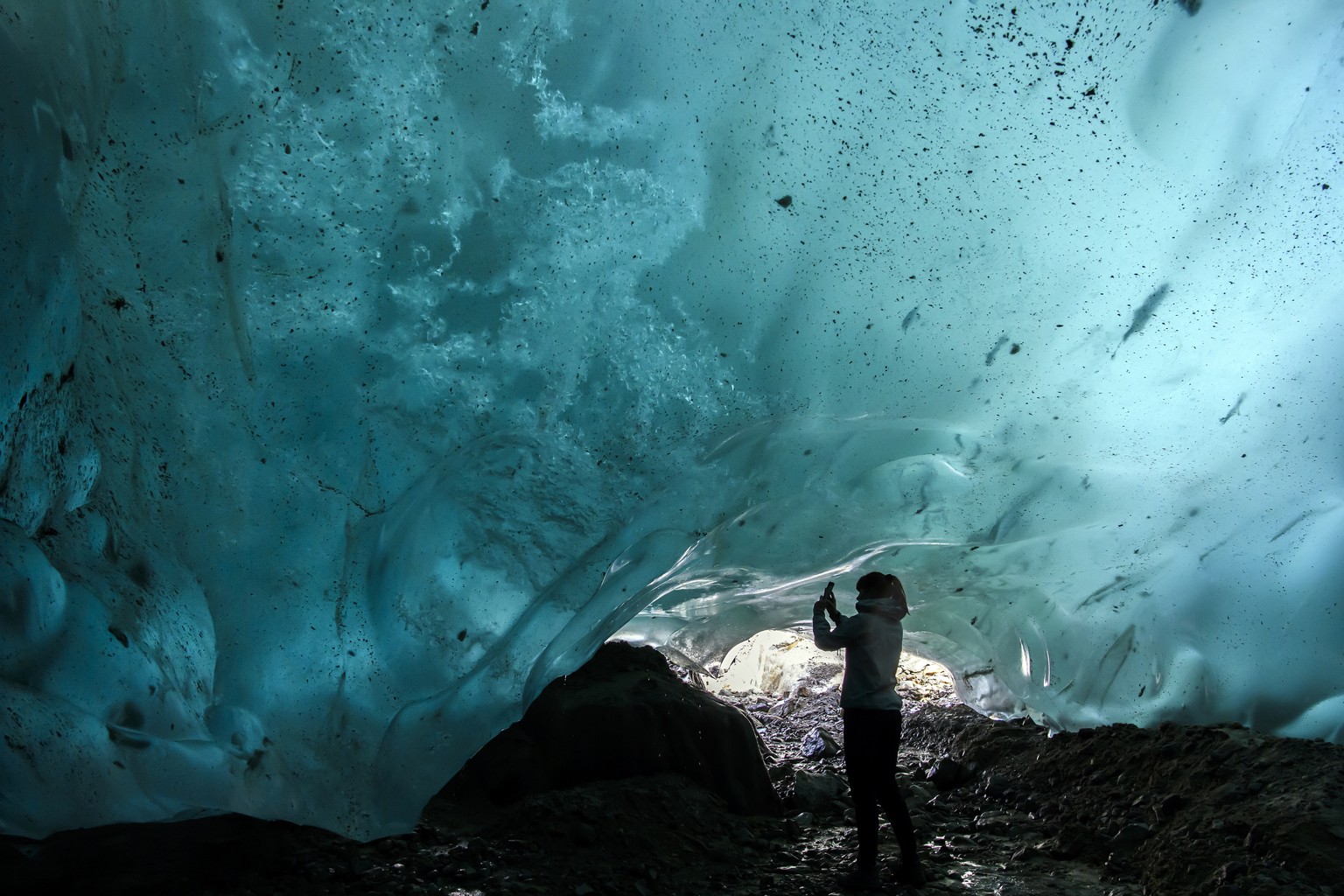 Stefanie takes a picture in an ice cave in the Swiss Aletsch Glacier, during an autumn day, in Valais, Switzerland, Wednesday, September 25, 2019. The Swiss Aletsch glacier, one of the largest ice str ...