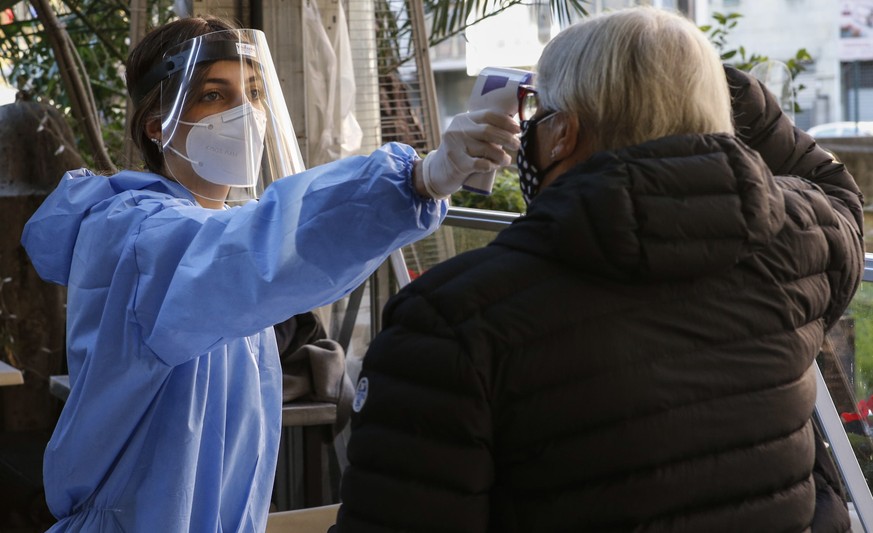 epa08829391 A Health personnel checks a body temperature before performing a coronavirus covid-19 quick test at a makeshift test center near the centre of Rome, Italy, 19 November 2020, amid the secon ...